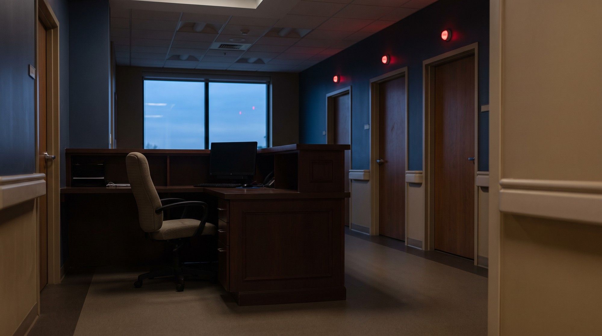 Empty nurses' station with call lights glowing down a nursing home hallway, showing understaffing. Illustration for California Nursing Home Neglect Attorneys.